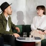 man in white button up shirt sitting beside woman in green blazer